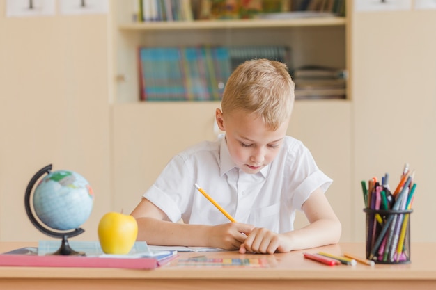 Niño escribiendo en el cuaderno durante la lección