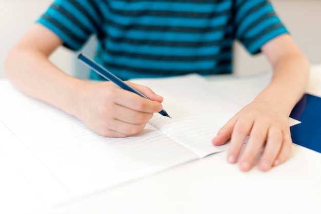 Foto gratuita niño escribiendo en un cuaderno vacío