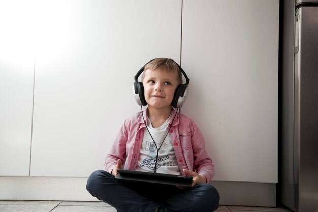 Niño escuchando música en el piso