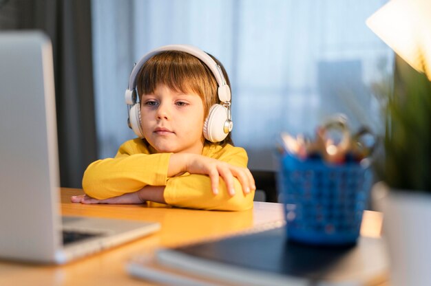 Niño de escuela en camisa amarilla tomando clases virtuales vista frontal