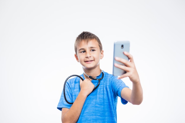 Foto gratuita niño con estetoscopio tomando selfie con smartphone