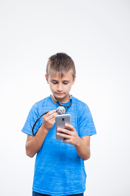 Niño con estetoscopio usando teléfono móvil