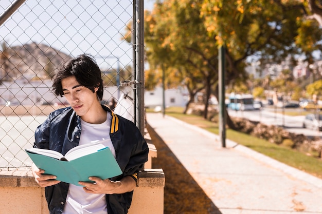 Niño étnico leyendo el libro con cuidado