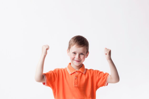 Niño feliz apretando el puño haciendo gesto de sí en la pared blanca