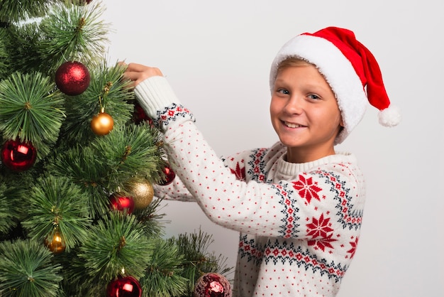 Niño feliz decorando el árbol de navidad