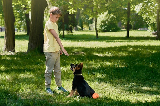 Niño feliz entrenando cachorrito en el parque de la ciudad