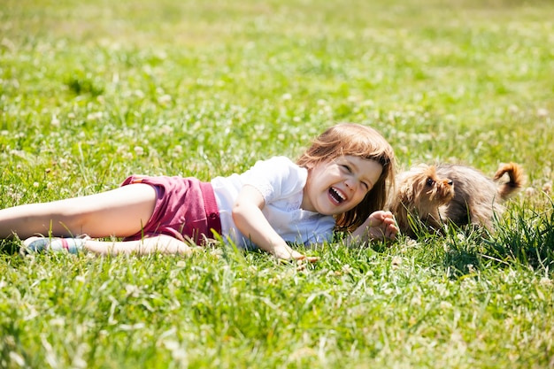 Niño feliz jugando con el cachorro en el prado en verano