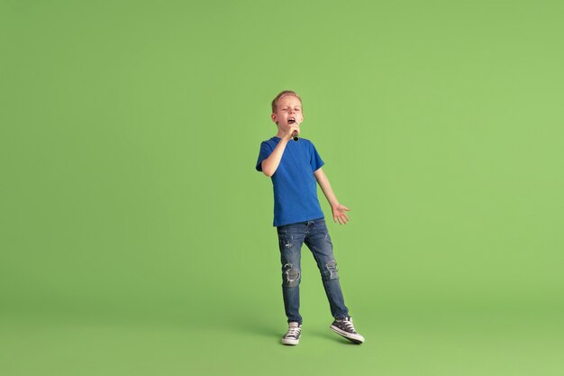 Niño feliz jugando y divirtiéndose en la pared verde del estudio