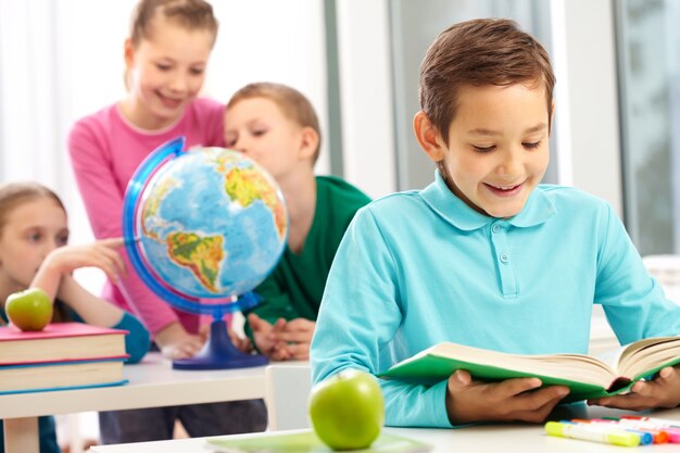 Niño feliz leyendo un libro junto a una manzana