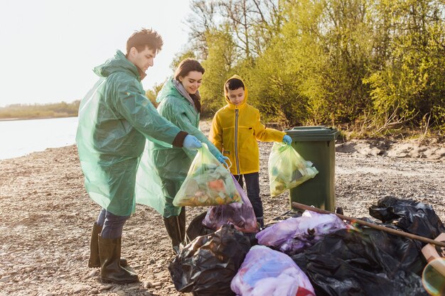 Niño feliz con los padres que sostienen el paquete para botellas de plástico y ahorran la contaminación juntos