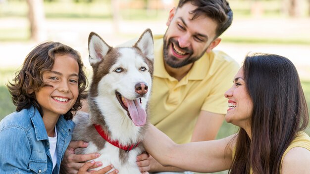 Niño feliz posando en el parque con perro y padres