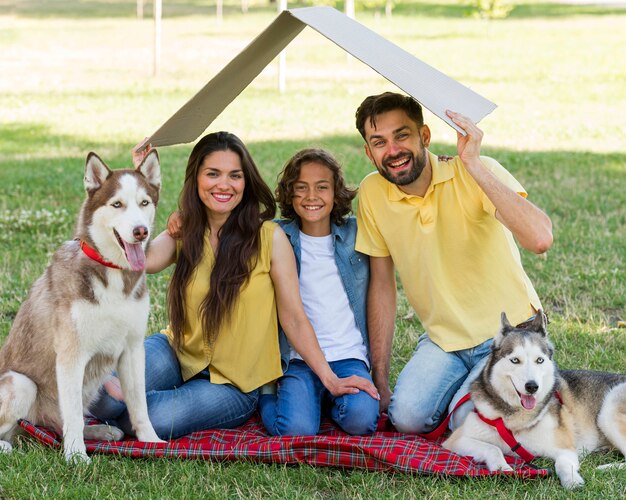 Niño feliz posando en el parque con perros y padres