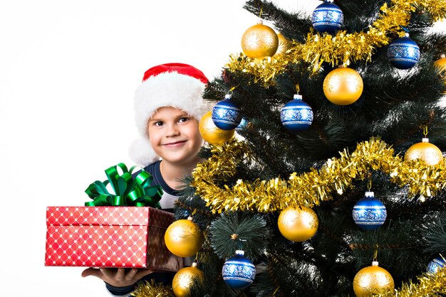 Niño feliz con regalo cerca del árbol de Navidad