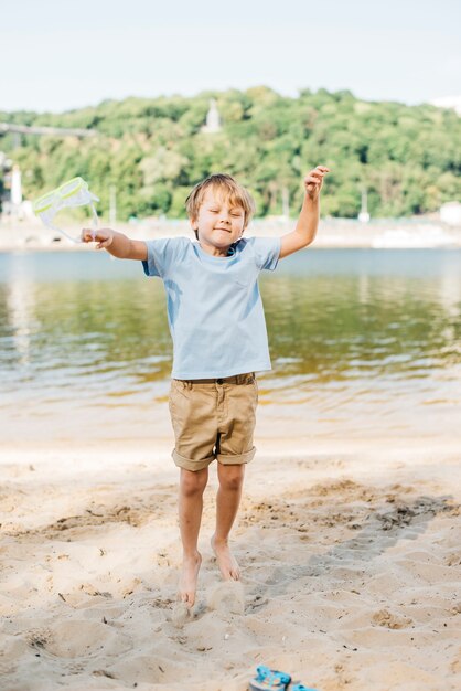 Niño feliz saltando en la orilla arenosa