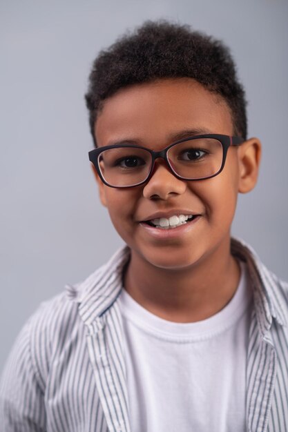 Niño feliz sonriente en espectáculos mirando hacia adelante