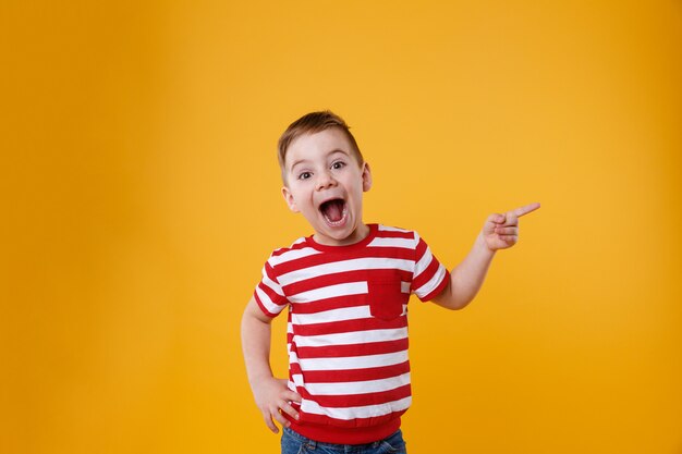 Niño feliz sorprendido apuntando los dedos hacia arriba