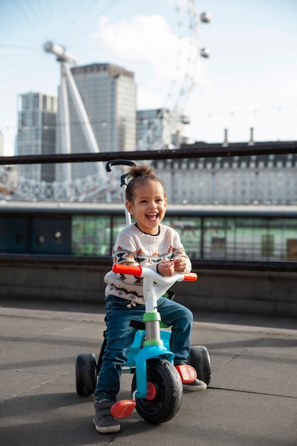 Niño feliz de tiro completo en triciclo al aire libre