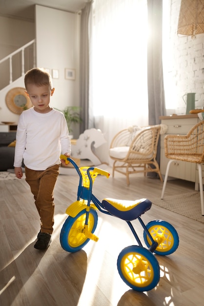 Niño feliz de tiro completo con triciclo en el interior