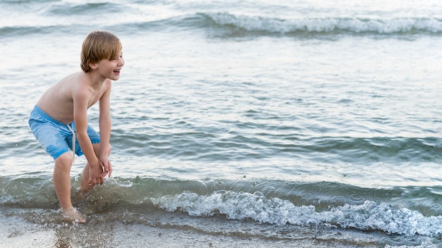 Niño feliz de tiro medio en la playa