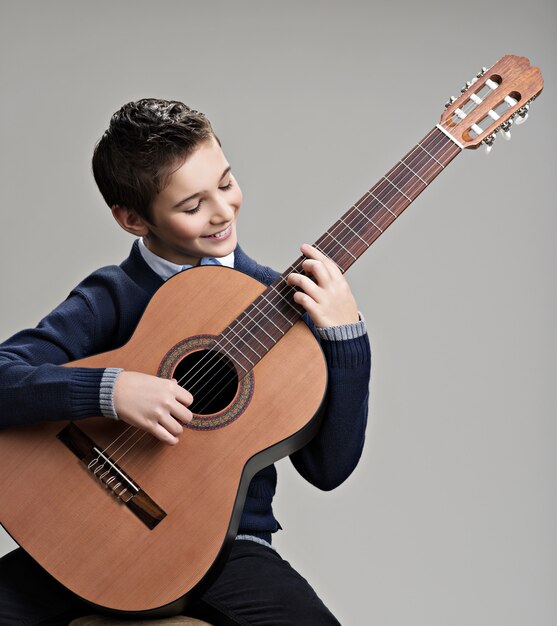 Niño feliz tocando la guitarra acústica.