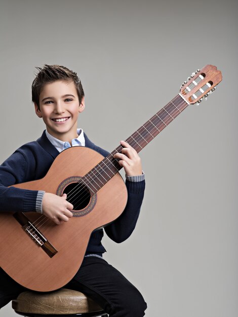 Niño feliz tocando la guitarra acústica.