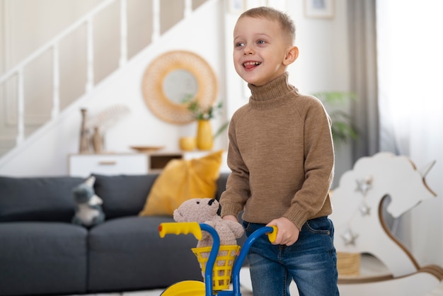 Niño feliz con triciclo en el interior tiro medio