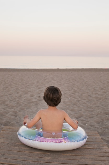 Niño con flotador junto al mar