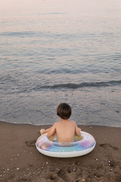 Foto gratuita niño con flotador junto al mar