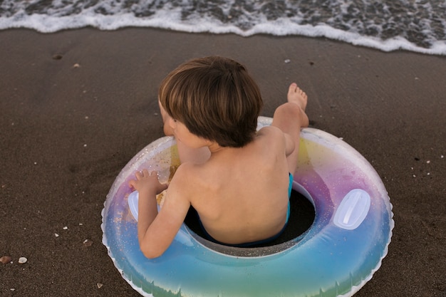 Foto gratuita niño con flotador junto al mar