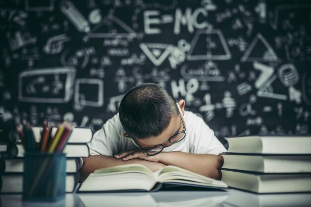 Un niño con gafas estudiando y somnoliento.