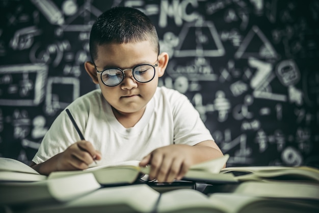 Un niño con gafas hombre escribiendo en el aula.