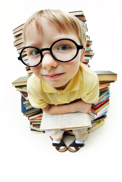 Niño con gafas rodeado de libros