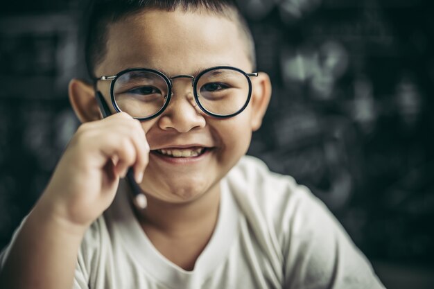 Foto gratuita un niño con gafas sentado en el aula estudiando.