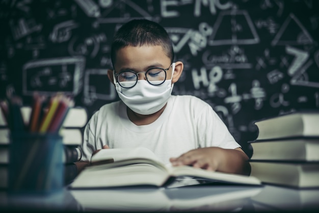 Un niño con gafas sentado en el aula leyendo.