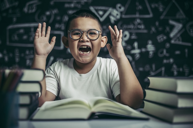 Un niño con gafas sentado en el aula leyendo.