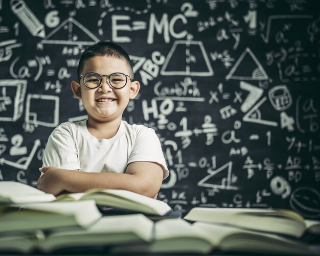 Un niño con gafas sentado en el aula leyendo.