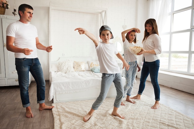 Niño con gorra y bailando delante de sus padres y su hermana en casa