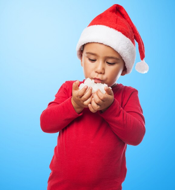 Niño con gorro de santa jugando con la nieve