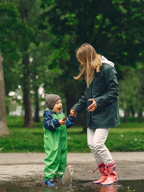 Niño gracioso en botas de lluvia jugando en un parque de lluvia