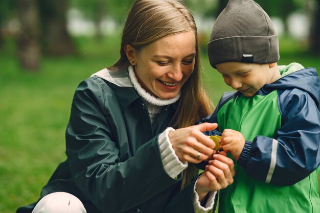 Niño gracioso en botas de lluvia jugando en un parque de lluvia