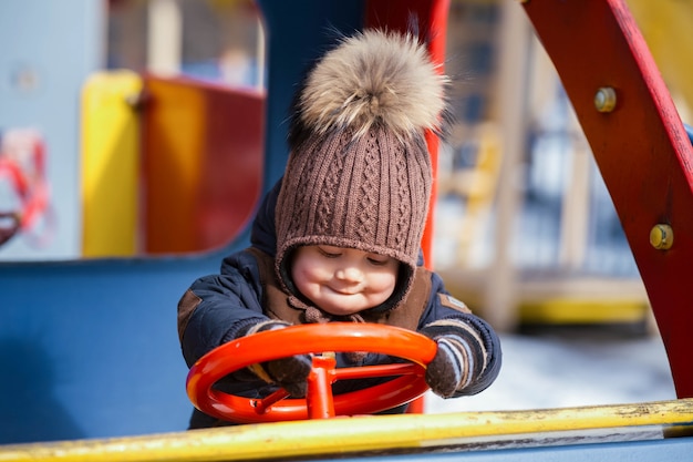 Niño gracioso juega con un coche de juguete en el parque