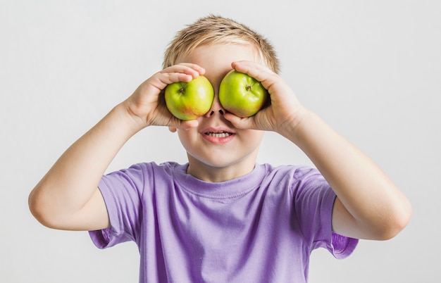 Foto gratuita niño gracioso con manzanas verdes