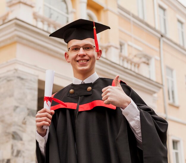 Niño graduado que muestra signo ok