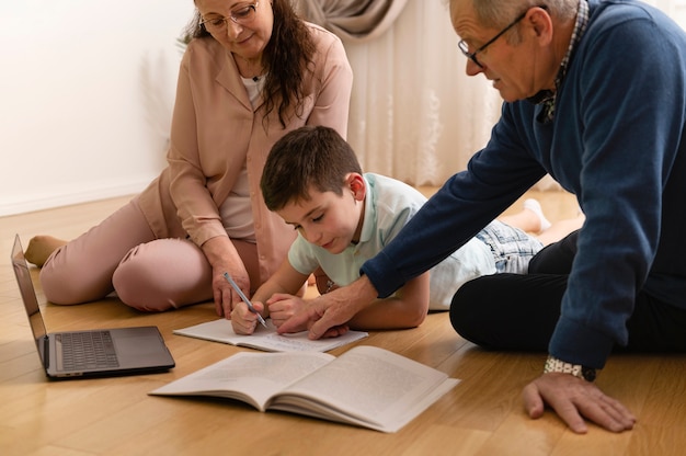 Niño haciendo los deberes con sus abuelos en casa