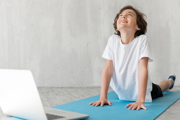 Niño haciendo deporte junto a una computadora portátil