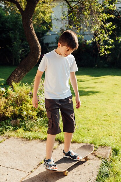 Niño inocente jugando skate en el parque