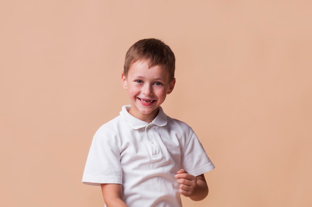 Niño inocente sonriente sobre fondo beige