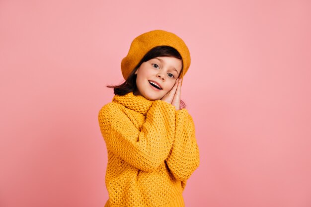 Niño inspirado posando en la pared rosa. niña preadolescente de pelo corto.