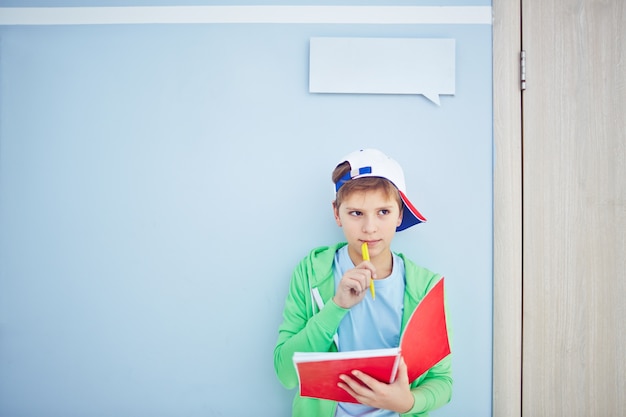 Niño inteligente pensando con una libreta