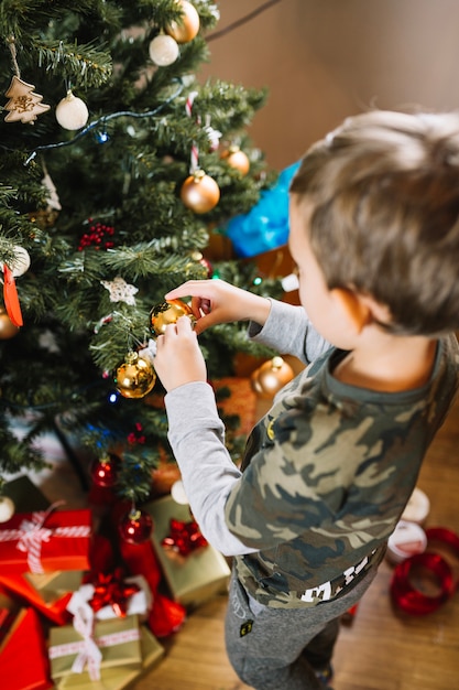 Niño joven decorando árbol de navidad